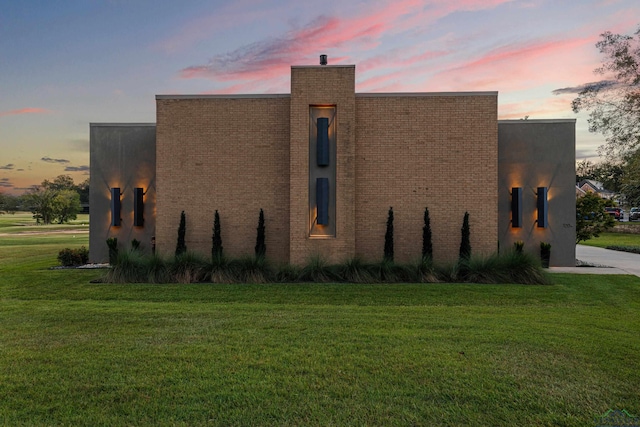 property exterior at dusk with a lawn