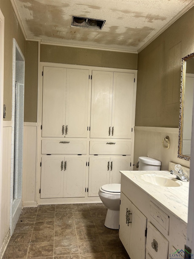 bathroom with vanity, ornamental molding, a shower with shower door, and toilet