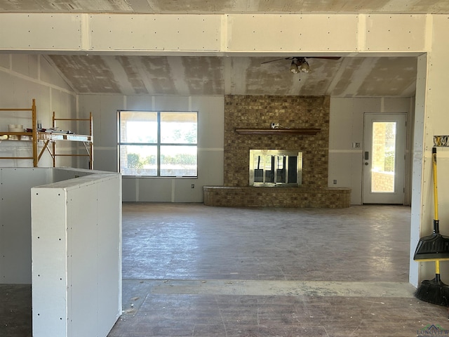 unfurnished living room with ceiling fan, a fireplace, and lofted ceiling