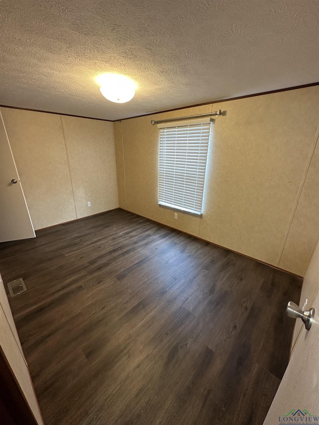 12700 2184 D, Tatum, TX 75691 - unfurnished bedroom with dark wood-style floors and a textured ceiling
