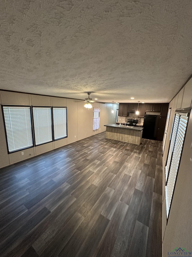 12700 2184 D, Tatum, TX 75691 - unfurnished living room featuring dark wood-style flooring, a ceiling fan, and a textured ceiling