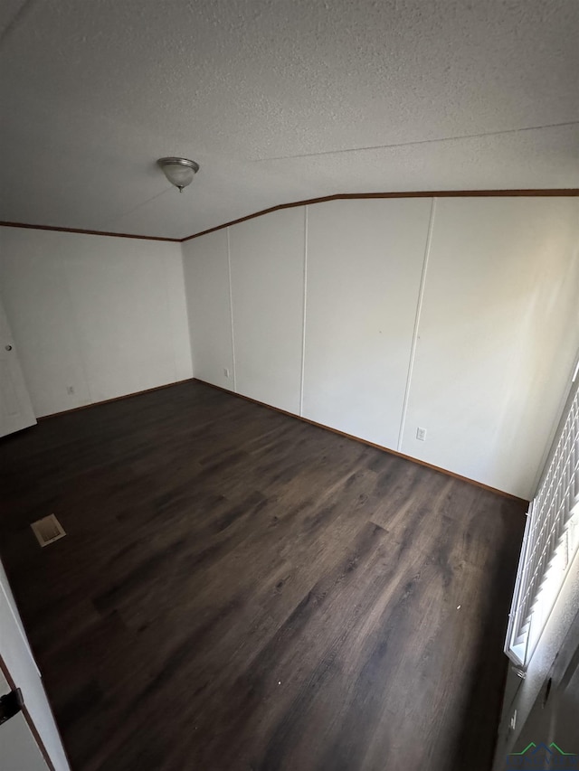 12700 2184 D, Tatum, TX 75691 - unfurnished bedroom with dark wood-style floors, a textured ceiling, and a decorative wall