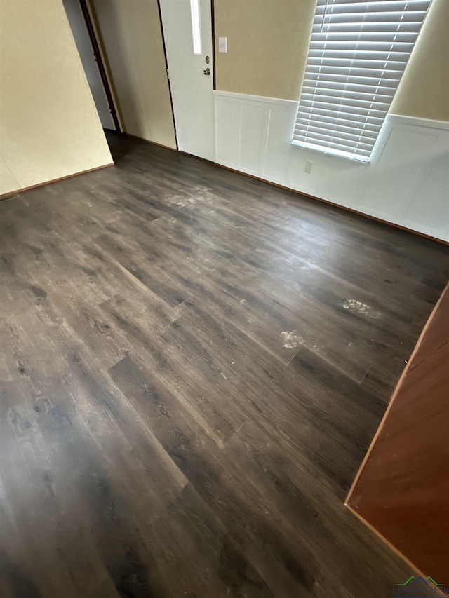 12700 2184 D, Tatum, TX 75691 - unfurnished room with dark wood-style floors, wainscoting, and a decorative wall
