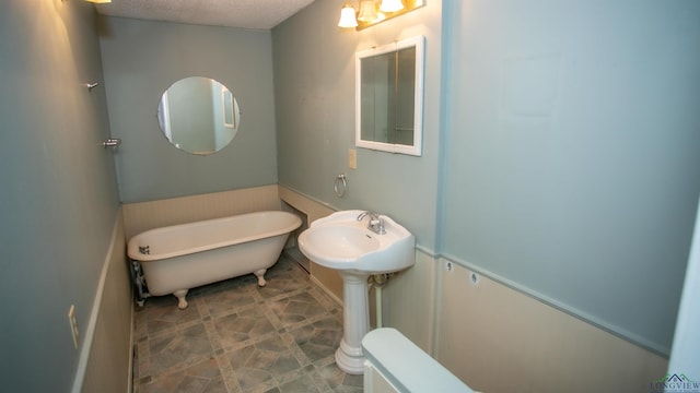 bathroom featuring a washtub and a textured ceiling