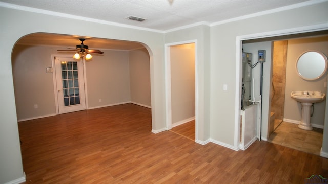 unfurnished room with ceiling fan, sink, crown molding, a textured ceiling, and hardwood / wood-style flooring