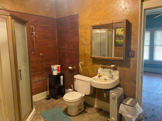 bathroom featuring an enclosed shower, toilet, radiator, and sink