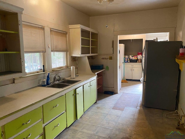 kitchen with stainless steel fridge, green cabinetry, and sink