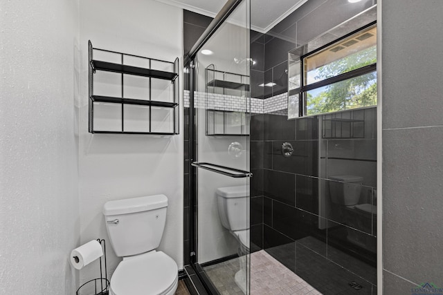 bathroom featuring toilet, a shower with door, and ornamental molding