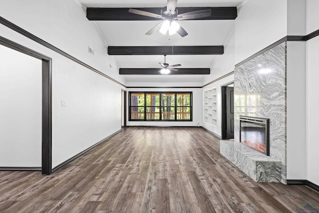 unfurnished living room with vaulted ceiling with beams, ceiling fan, a stone fireplace, and dark hardwood / wood-style flooring