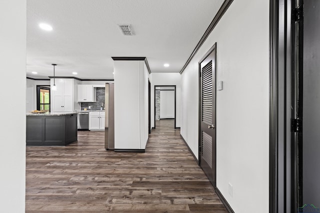 hall featuring dark wood-type flooring, a textured ceiling, and ornamental molding