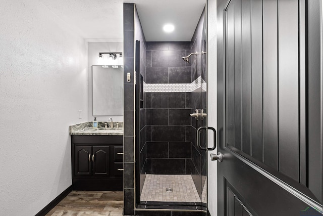 bathroom featuring wood-type flooring, vanity, and a shower with shower door