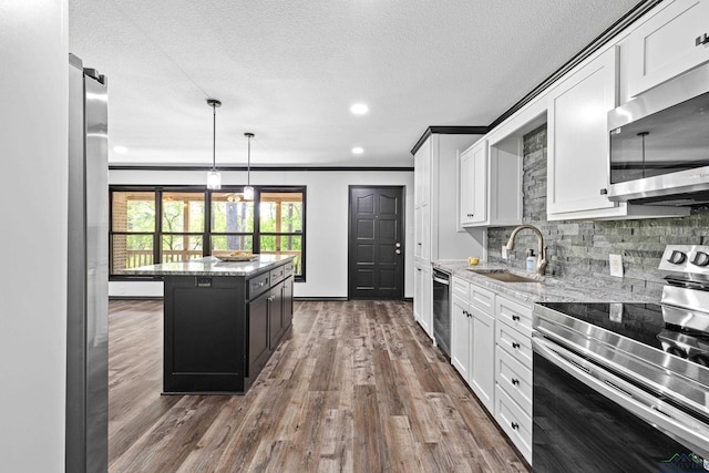 kitchen with sink, a kitchen island, light stone counters, white cabinetry, and stainless steel appliances