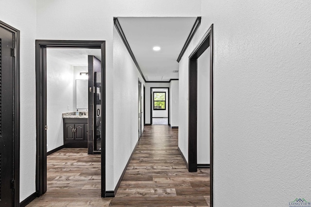 hallway with dark hardwood / wood-style floors, crown molding, and sink