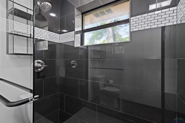 bathroom with tiled shower and toilet