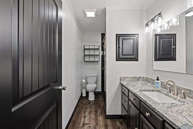 bathroom with crown molding, vanity, wood-type flooring, and toilet