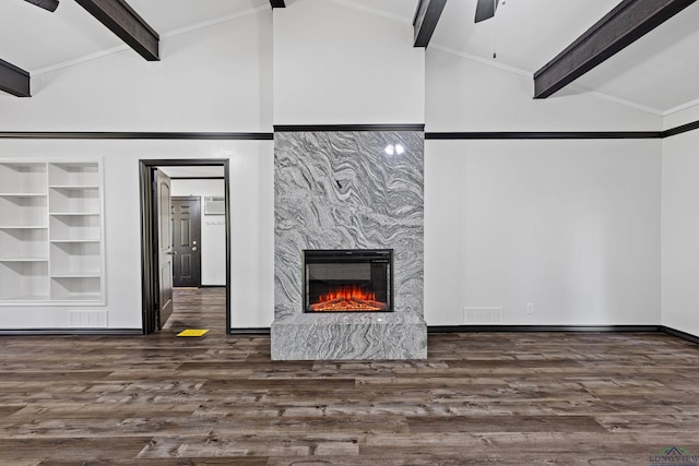 living room with built in shelves, ceiling fan, dark wood-type flooring, a high end fireplace, and lofted ceiling with beams