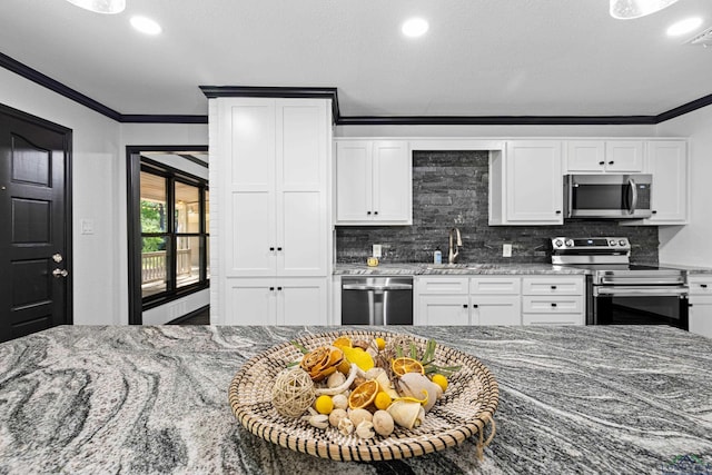 kitchen featuring backsplash, dark stone countertops, white cabinetry, and appliances with stainless steel finishes