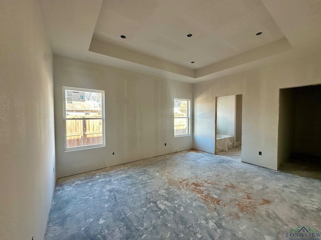 unfurnished bedroom with ensuite bath and a tray ceiling