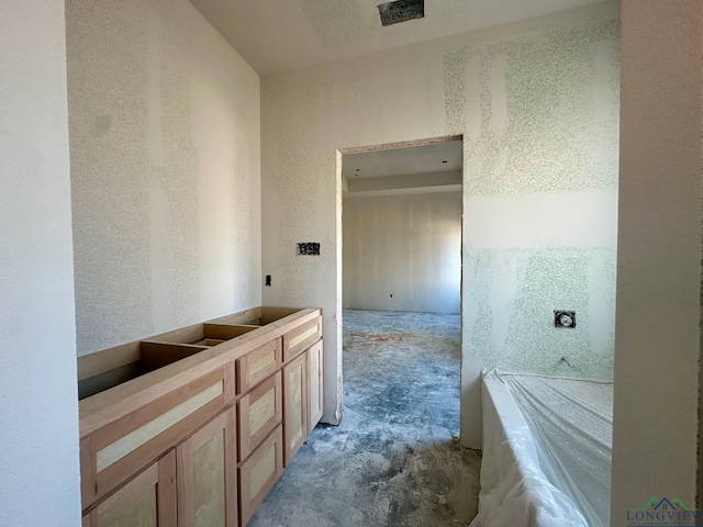 bathroom with concrete floors and a tub to relax in