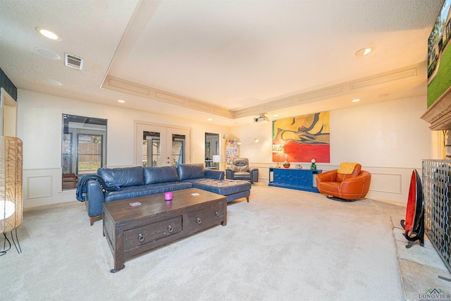 carpeted living room featuring french doors and a tray ceiling