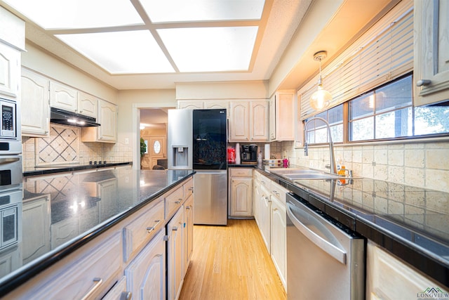 kitchen with sink, stainless steel appliances, backsplash, pendant lighting, and light wood-type flooring