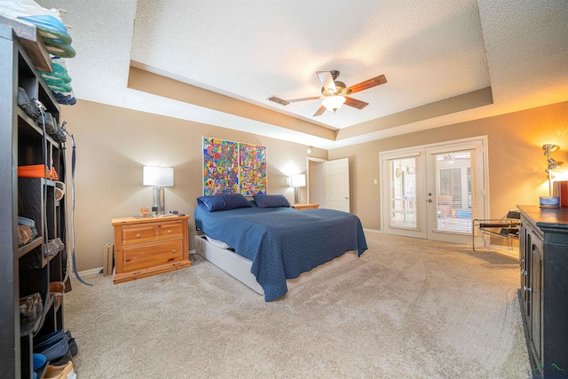 carpeted bedroom featuring a raised ceiling, access to exterior, ceiling fan, and a textured ceiling