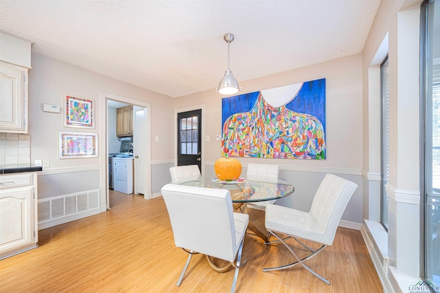 dining area with independent washer and dryer, a textured ceiling, and light hardwood / wood-style floors