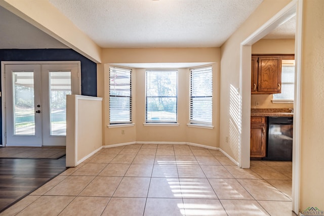 interior space featuring french doors, a textured ceiling, and light tile patterned floors