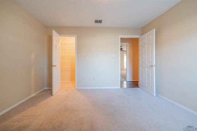 unfurnished bedroom with light colored carpet, a spacious closet, and a closet