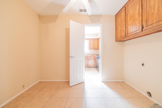 washroom featuring electric dryer hookup, light tile patterned floors, and cabinets