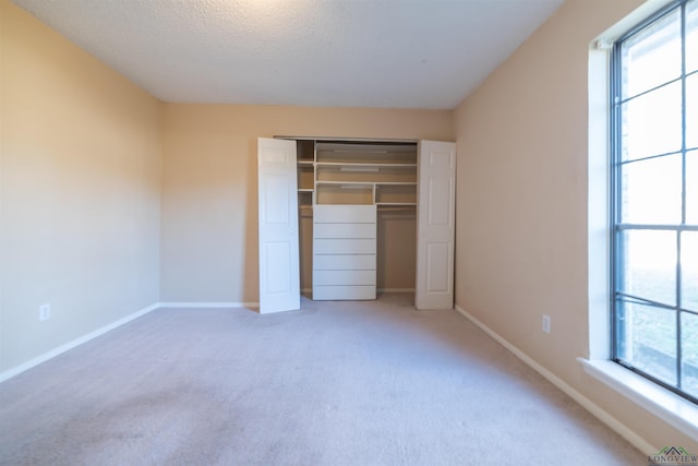 unfurnished bedroom featuring a textured ceiling, a closet, multiple windows, and carpet flooring