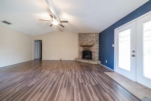 unfurnished living room featuring hardwood / wood-style flooring, lofted ceiling with beams, a healthy amount of sunlight, a fireplace, and ceiling fan