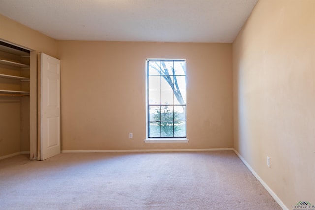 unfurnished bedroom with light colored carpet and a closet