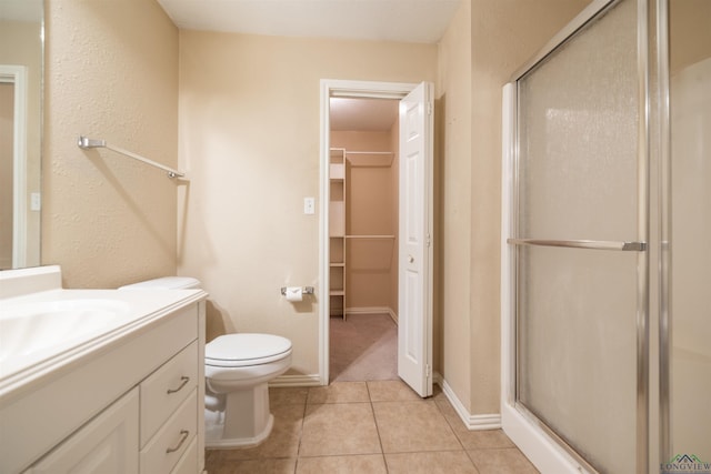 bathroom with toilet, a shower with door, vanity, and tile patterned floors