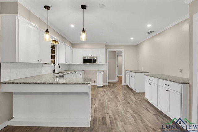 kitchen with light stone countertops, pendant lighting, white cabinets, sink, and kitchen peninsula