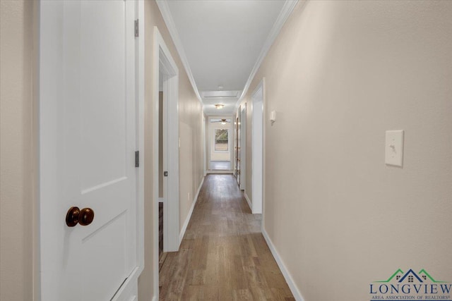 corridor with ornamental molding and hardwood / wood-style floors