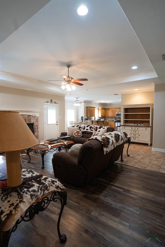 3713 Bell Mdws, Longview, TX 75605 - living area featuring a brick fireplace, a tray ceiling, ceiling fan, light wood-type flooring, and recessed lighting