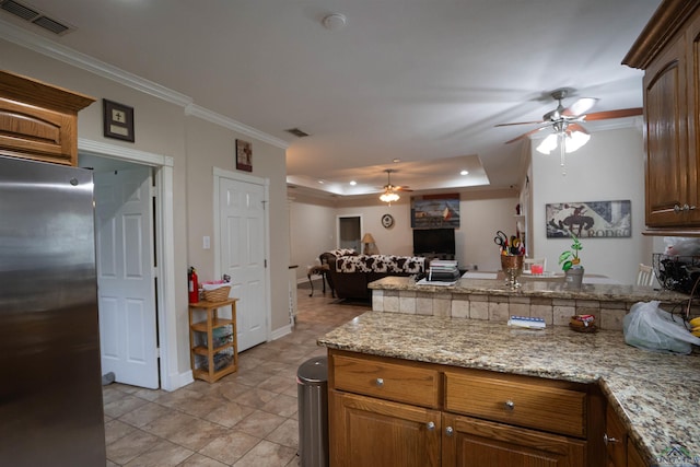 3713 Bell Mdws, Longview, TX 75605 - kitchen with freestanding refrigerator, a ceiling fan, open floor plan, a peninsula, and ornamental molding
