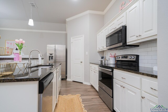 2931 Meadow Brook Trl, Tyler, TX 75701 - kitchen featuring stainless steel appliances, decorative backsplash, white cabinets, light wood-style floors, and decorative light fixtures