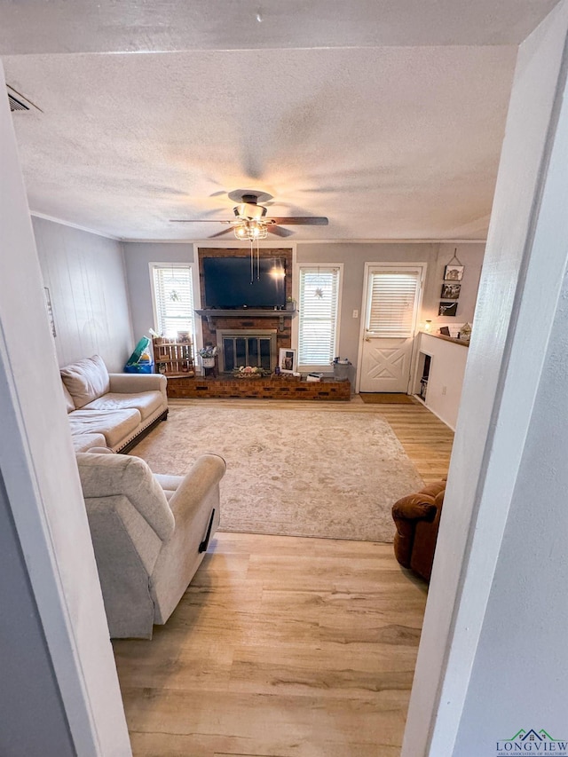 902 Warren Dr, Marshall, TX 75672 - living room featuring wood finished floors, ceiling fan, a glass covered fireplace, and a textured ceiling