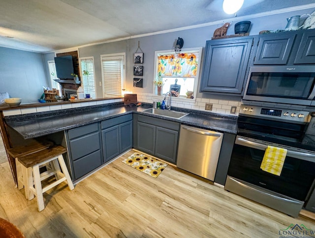 902 Warren Dr, Marshall, TX 75672 - kitchen with appliances with stainless steel finishes, a peninsula, light wood-style flooring, ornamental molding, and dark countertops