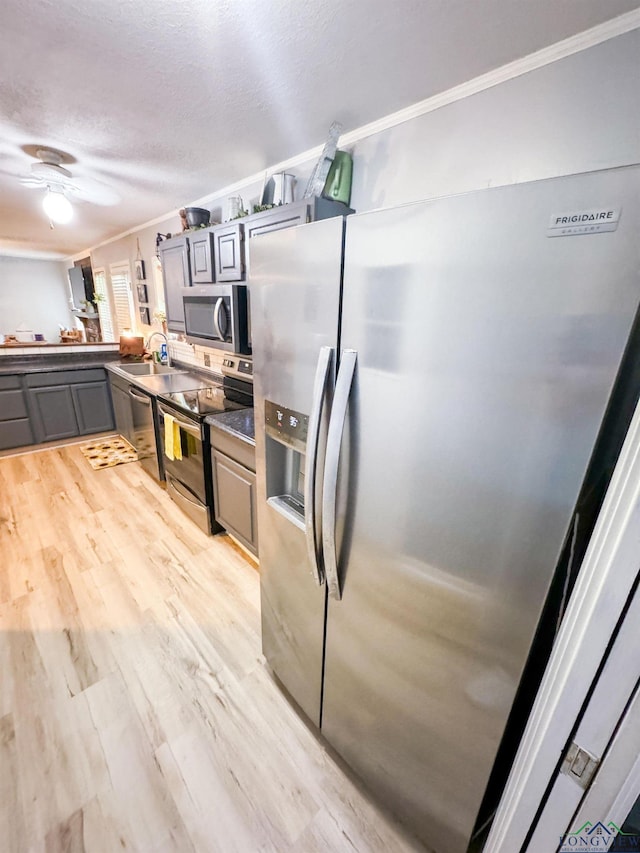 902 Warren Dr, Marshall, TX 75672 - kitchen featuring stainless steel appliances, gray cabinetry, ornamental molding, light wood-style flooring, and a ceiling fan