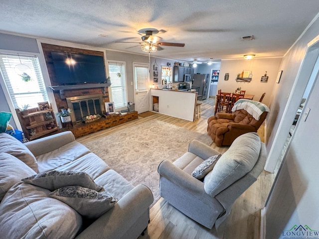902 Warren Dr, Marshall, TX 75672 - living room with ceiling fan, light wood finished floors, a textured ceiling, and a fireplace