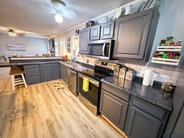 902 Warren Dr, Marshall, TX 75672 - kitchen featuring stainless steel appliances, ceiling fan, gray cabinetry, crown molding, and decorative backsplash
