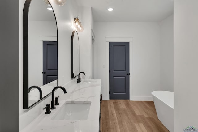 1507 Wellington Ln, Longview, TX 75605 - bathroom with a soaking tub, double vanity, wood finished floors, recessed lighting, and baseboards