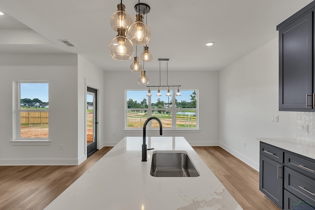 1507 Wellington Ln, Longview, TX 75605 - kitchen with a sink, light stone counters, light wood-style flooring, baseboards, and recessed lighting