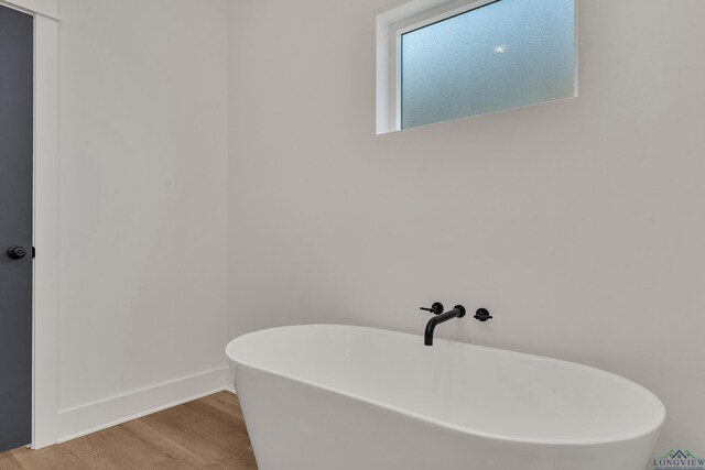 1507 Wellington Ln, Longview, TX 75605 - full bathroom featuring a freestanding tub, wood finished floors, and baseboards