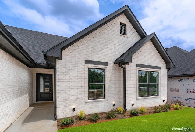 1507 Wellington Ln, Longview, TX 75605 - doorway to property with brick siding, roof with shingles, and a yard