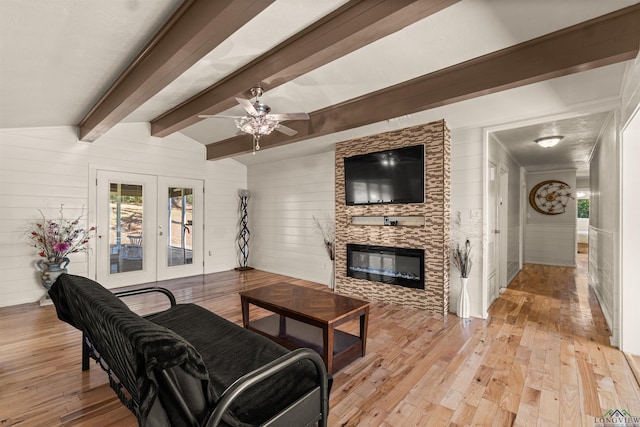 living room featuring french doors, lofted ceiling with beams, a stone fireplace, and wooden walls