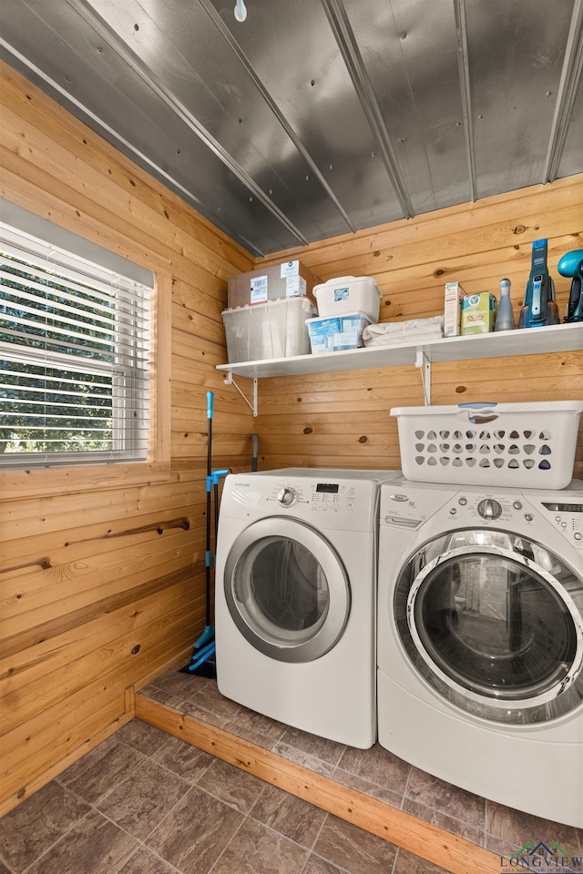 clothes washing area featuring washer and clothes dryer and wooden walls